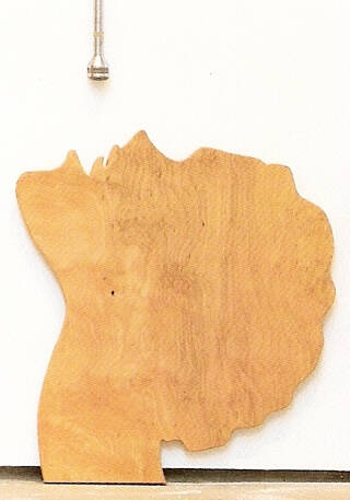 Wood sculpture profile of a woman's head with a microphone dangling above it.
